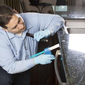professional pest technician applying product to kitchen counters